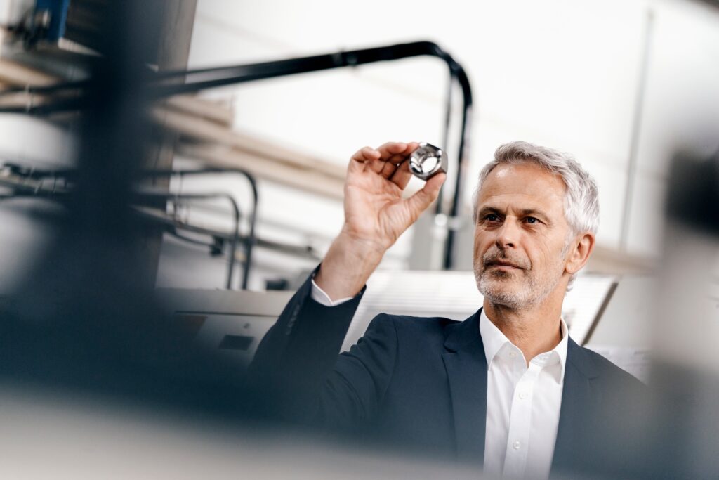 Manager in high tech enterprise, checking machine parts